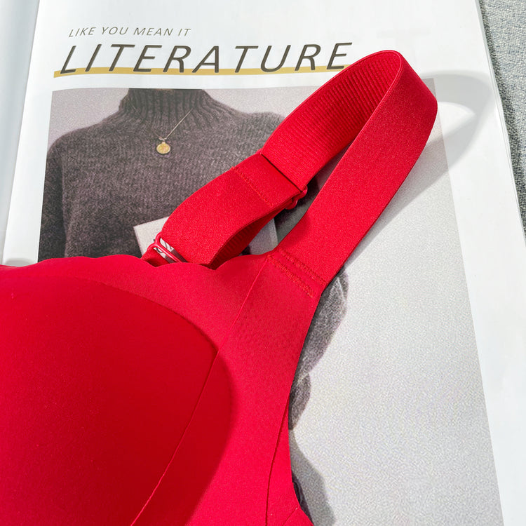 A top view of a red wireless bra laid out on a flat surface, showing the smooth fabric and wide shoulder straps.