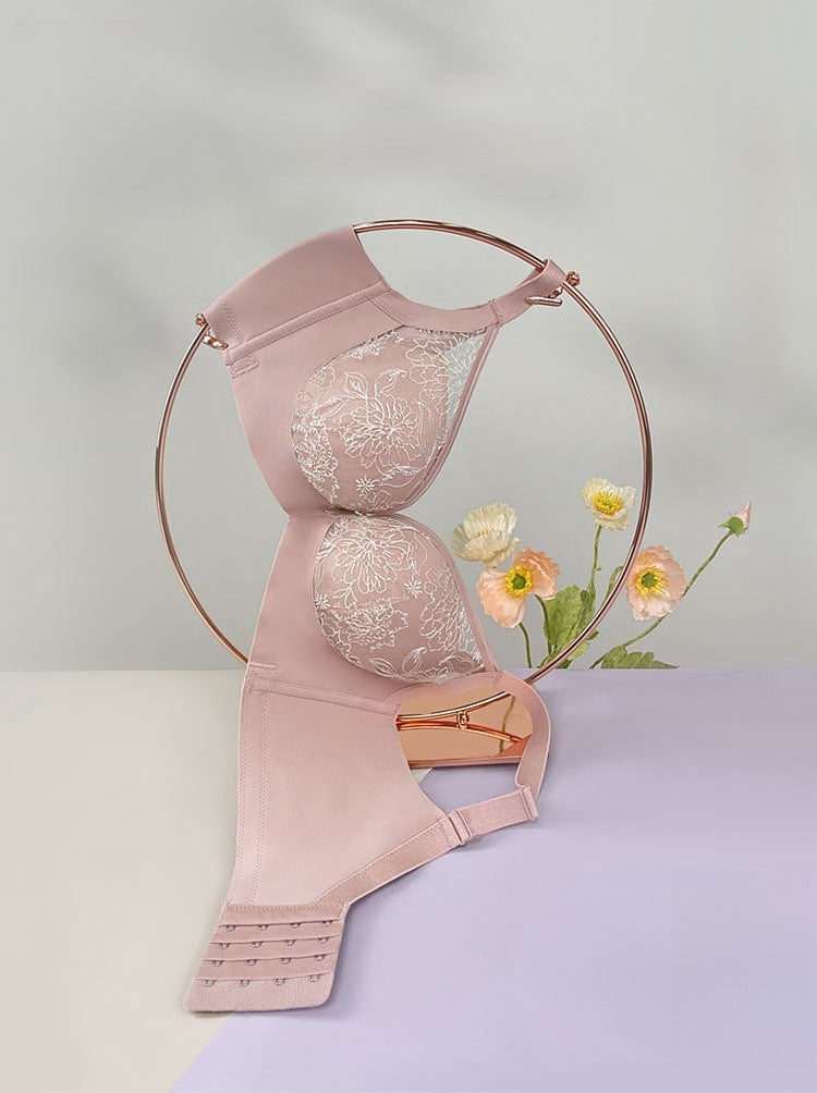 Pink floral embroidered lace bra with medium-thick molded cups displayed on a stand, highlighting its detailed lace and elegant design.